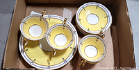 Aynsley cups and saucers with yellow band and gold handles, stacked in a box