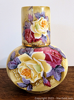 Front view of hand painted porcelain covered vase showing detailed rose and leaf floral painting with yellow, red, and purple colors.