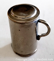 Closeup of the small silver cylindrical lighter body with a handle and flat top.