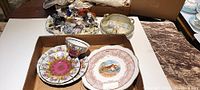 Wide shot of all items in the lot showing the figurine, teacup with saucer, and calendar plate arranged on a white surface.