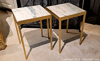 Two side tables angled front view showing marble tops and gold frames