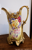 Front view showing detailed floral motif and gold accents on the handle and spout