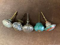 Top view of five decorative drawer pulls showing varied knob styles and attached screws
