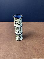 Front view of a small cloisonné vase decorated with pandas and bamboo on a cream background with blue interior and gold trim.