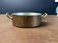 Front view of small copper pot showing two loop handles and hammered texture.