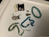 Overview of all jewelry items including earrings, bracelets, and pins showing Day of the Dead and spider motifs.