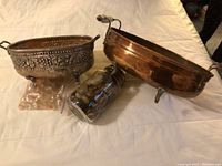 Photo of two decorative planters and a jar of clear glass stones on a white cloth surface.