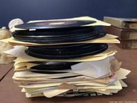 Stack of vintage 45 RPM records with visible sleeves and some loose paper inserts