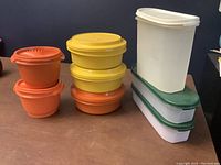 Orange, yellow, and white rectangular Tupperware containers with lids, various sizes and stackable.