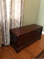Side view of the Powell cedar chest showing shape and finish, with visible corner damage.