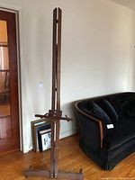 Front view of the vintage wooden easel showing its height, structure, and wooden finish with scratches.