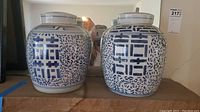 Pair of two blue and white covered ginger jars on a wooden surface, showing their shape and top.