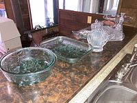 Overview of glassware items including baking dishes, bowls, candy dish, napkin holder, and cruet on counter