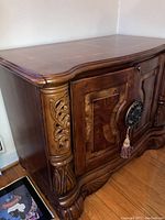 Full view of wood sideboard featuring carved details and marquetry inlay.