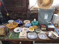 Overview of assorted ashtrays of varying materials and colors alongside matchboxes.