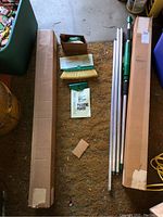 Two boxed kits and cleaning tools laid out on garage floor. Components include brush heads, manual, metal rods, and boxes.