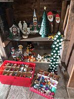 Shelf overview showing ceramic church, log Santas, candy cane cutouts and ornament boxes