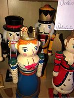 Photo showing several wood Christmas nutcrackers including a queen with a blue dress and crown, a king with a black hat, and other royal figures.