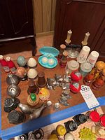 Arranged salt and pepper shakers of various types on a wooden surface including novelty and traditional designs