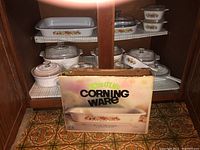 Full set of Corningware cookware including multiple covered casserole dishes and the boxed lasagna tray with vegetable pattern.