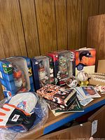 Photo showing Orioles gnomes in sealed MLB packaging, Cal Ripken Jr. memorabilia book, batting glove, collector baseball, cards, and other assorted Orioles items on a table.