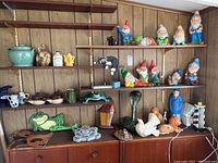 Wide view of shelves with yard gnomes and various decorative ceramic and garden items.