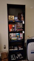 Front view of the tall dark wood bookcase filled with books and some decorative items, showing the overall height and shelf spacing.