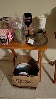 Overview of lot showing glasses, mugs, dishware on wooden table with plastic bag of dishes on floor