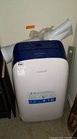 Honeywell portable air conditioner unit with attached exhaust hose and window vent kit visible from front.