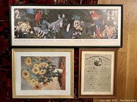 Three framed posters on a rug and wood floor: Audubon Zoological Garden animals scene, Monet sunflowers painting, and The Art Of Making Money poster