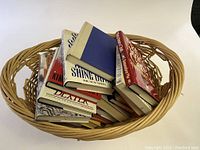 Basket with an assortment of books mixed and stacked facing different directions.
