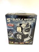 Front view of the original box showing the Jensen 5" black and white TV with AM/FM/public alert radio and lantern, highlighting the 5-way power feature and included RCA AV cable.