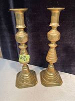 Photo showing a pair of solid brass antique candle holders with beehive style design and hexagonal bases on a white surface with a dark backdrop.