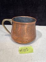 Photo of a solid copper antique cup with a brass handle and detailed Persian-style engraved decorations on the outer surface.