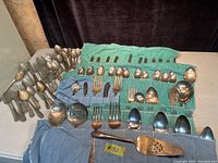 Full overview of all silverware in cloth holders showing spoons, forks, knives, and specialty serving utensils.