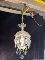Front angle photo of the small vintage crystal chandelier showing its hanging crystal prisms and chain suspension.
