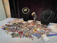 Wide shot of assorted jewelry pile with two busts displaying pearl and chain necklaces