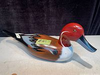 Side view of hand painted wood duck decoy showing vibrant red head, brown and black painted wings with feather details, and smooth glossy finish.