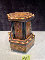 Photo showing the closed hexagonal wood box with detailed inlay and geometric designs on each side and top.