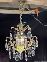 Full view of Mid Century Modern crystal chandelier hanging from ceiling with wired connection visible.