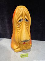 Front view showing dog's sad face with a tear and coin slot on top.