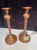 Pair of vintage solid copper candle holders shown on a light surface with a dark background, illustrating the shape and patina of each piece.