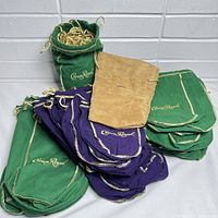 Pile of empty Crown Royal whiskey bottle bags including green, purple, and tan colors with some gold cords.