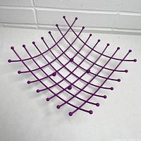 Front angled view of the deep purple wire fruit basket showing lattice design and rounded wire tips.