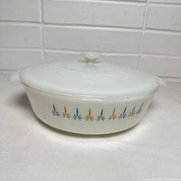Side view of the white milk glass Fire King casserole dish showing the colorful multi-color starburst pattern.