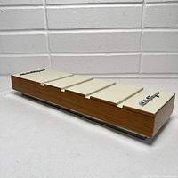 Picture of full rectangular store display showing wood base, cream grooves top and chrome logo.