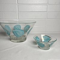 Photo shows a large clear glass chip bowl and a smaller matching dip bowl both decorated with hand-painted blue leaves and gold trim.