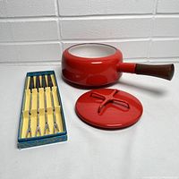 Photo of red enamel fondue pot with lid and set of 6 fondue forks in original blue and yellow box.