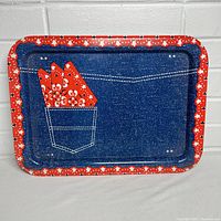 Top view of the metal lap tray showing the denim fabric print with sewn pocket holding four red floral handkerchiefs or napkins and a red polka dot edge border.