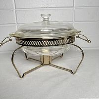 Side view of the assembled Fire King serving dish on the metal chafing stand with clear glass lid in place.